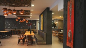 A modern restaurant interior with a long communal table, individual seating, and pendant lighting. - Gladiola Star (Golden Sands)