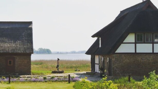 Een huis met een rieten dak, een wit raam en een stenen muur.