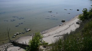 Een kustlandschap met een zandstrand, verspreide rotsen en een rustig waterlichaam.