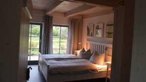 Een slaapkamer met twee bedden, een groot raam en uitzicht op groen.