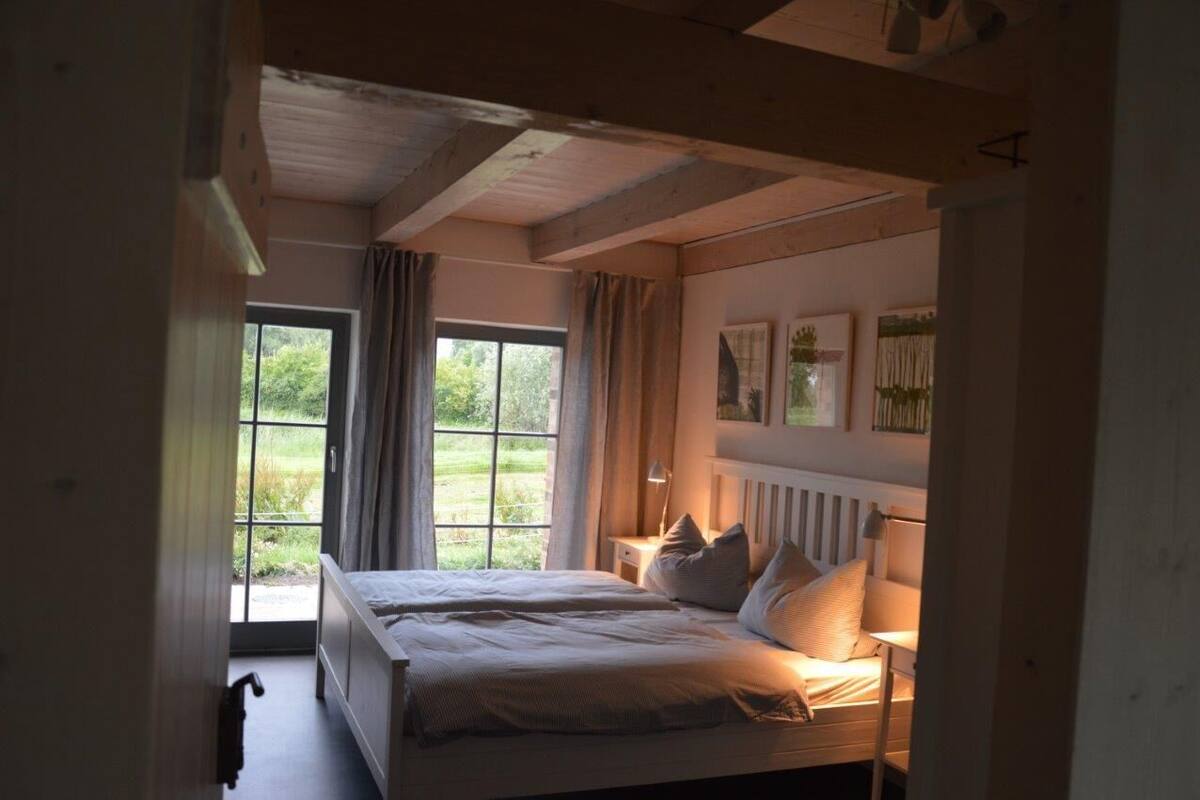 Quarto com duas camas, uma janela grande e vista para o verde lá fora.