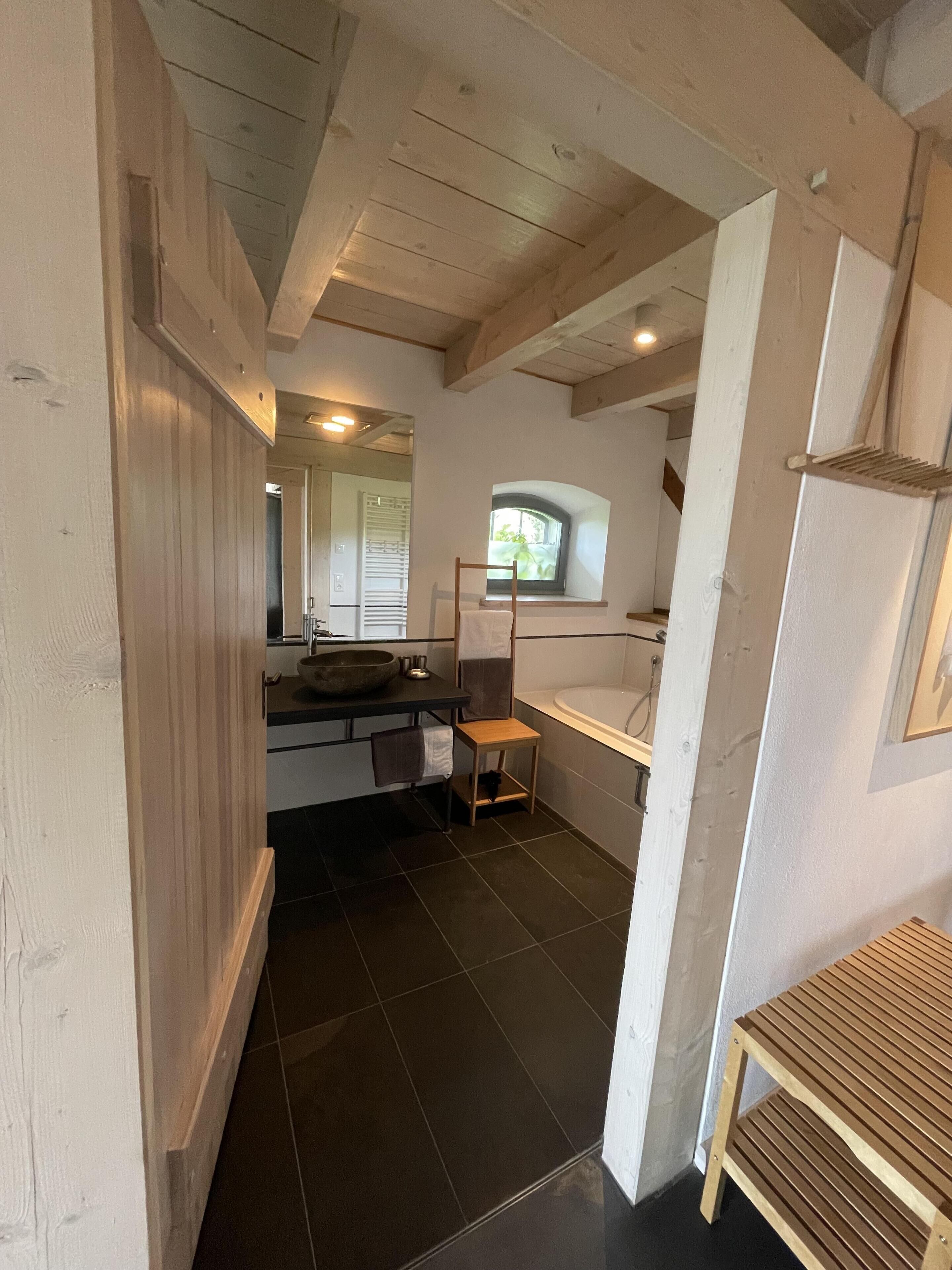 Un baño con tocador de madera, lavamanos y ventana.