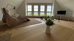 Een ruime kamer met een groot raam, een televisie en een plant.