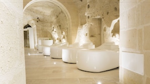 A spa area with modern white seating, stone walls, and a tiled floor.