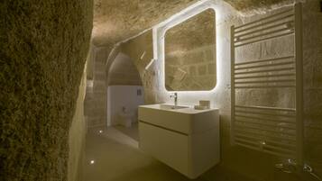 Un bagno con parete in pietra, lavabo, specchio e termosifone.