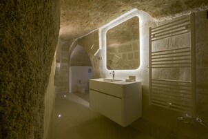 Un baño con pared de piedra, un lavamanos, un espejo y un radiador.