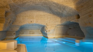 An indoor swimming pool with stone walls and a clear blue water surface.