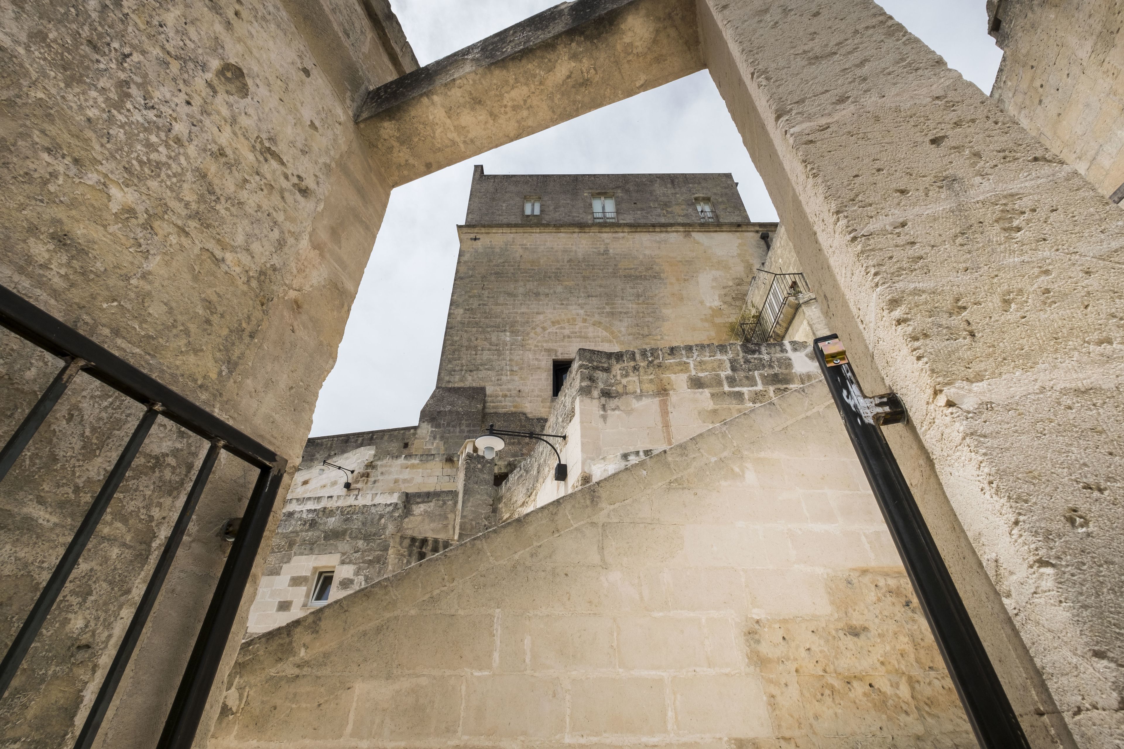 A stone building with a tower, featuring a staircase leading up to a door.