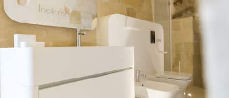 Un baño moderno con pared de piedra, un lavamanos blanco y un inodoro.