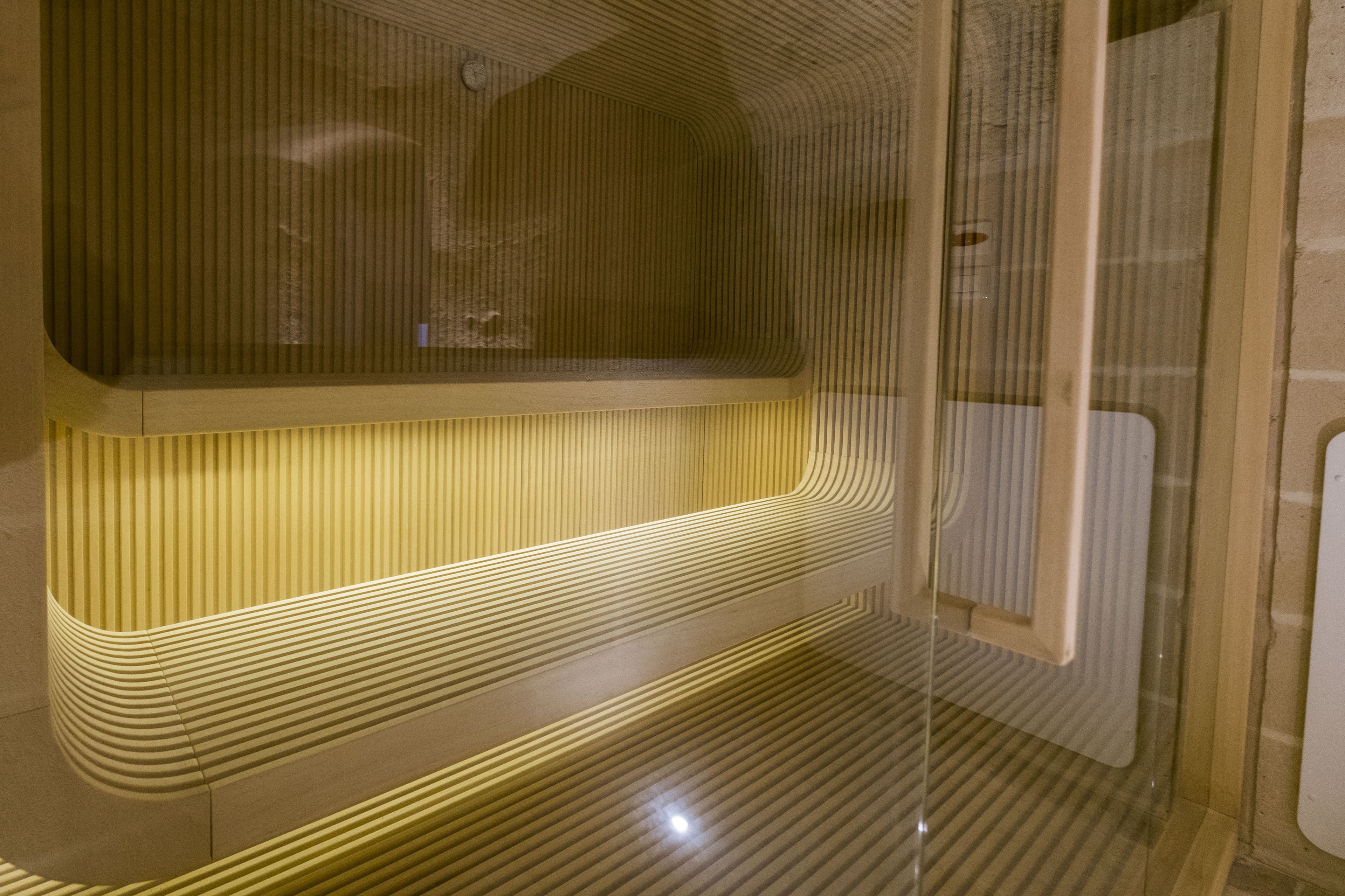 A modern, minimalist bathroom with ribbed walls and a bench.
