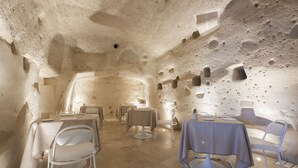 An interior with tables and chairs arranged in a cave-like setting, featuring natural rock walls and a tiled floor.