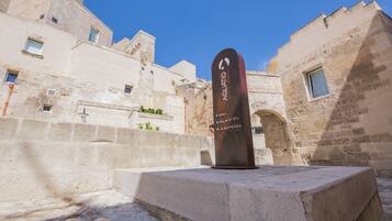 Un monumento in pietra con iscrizioni in un cortile circondato da edifici storici.