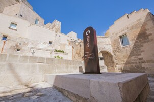 Monumento de piedra con inscripciones en un patio rodeado de edificios históricos.
