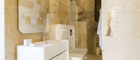 Une salle de bain moderne avec un mur en pierre, un lavabo blanc et des toilettes.