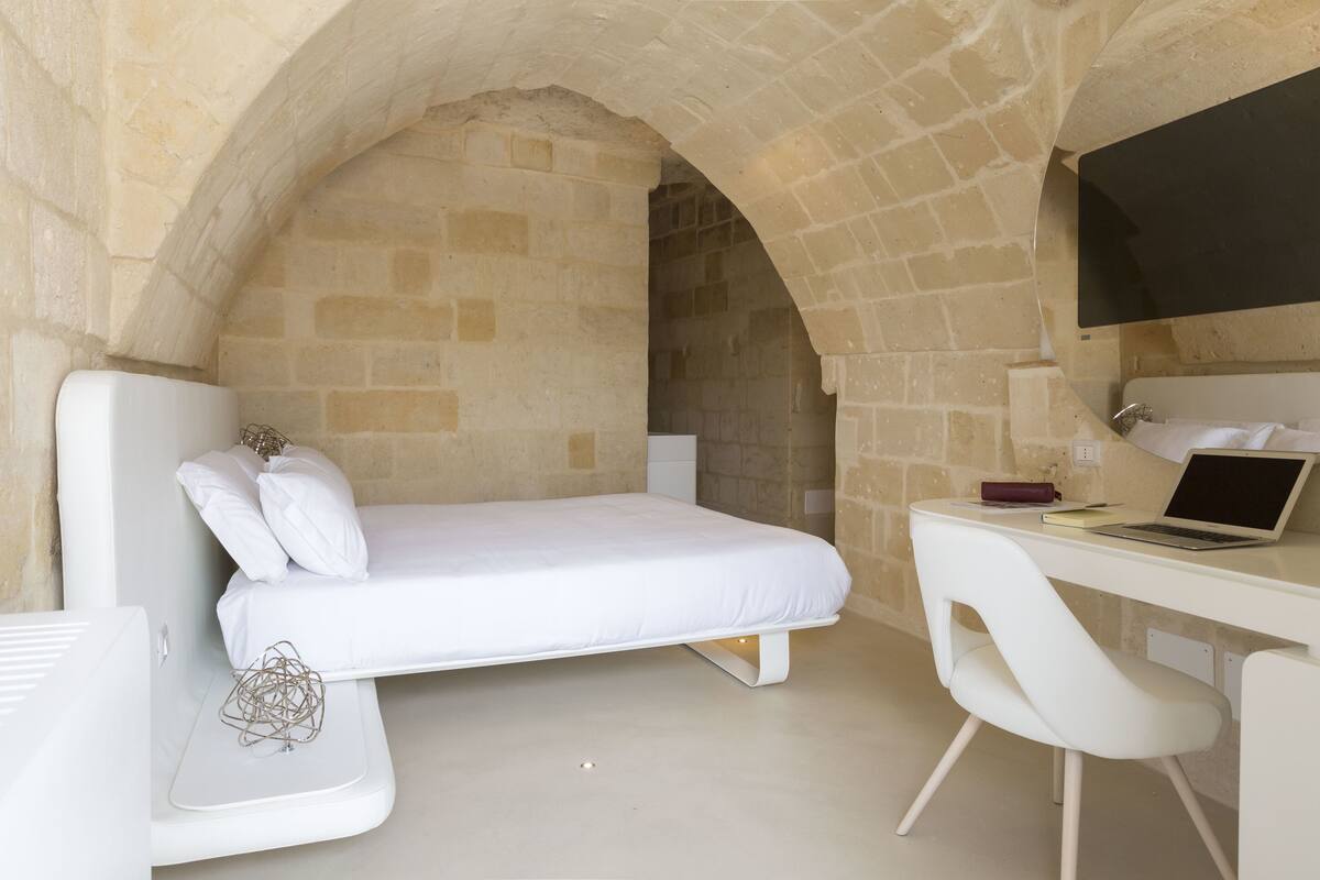 A modern bedroom with a bed, a desk, and a chair.