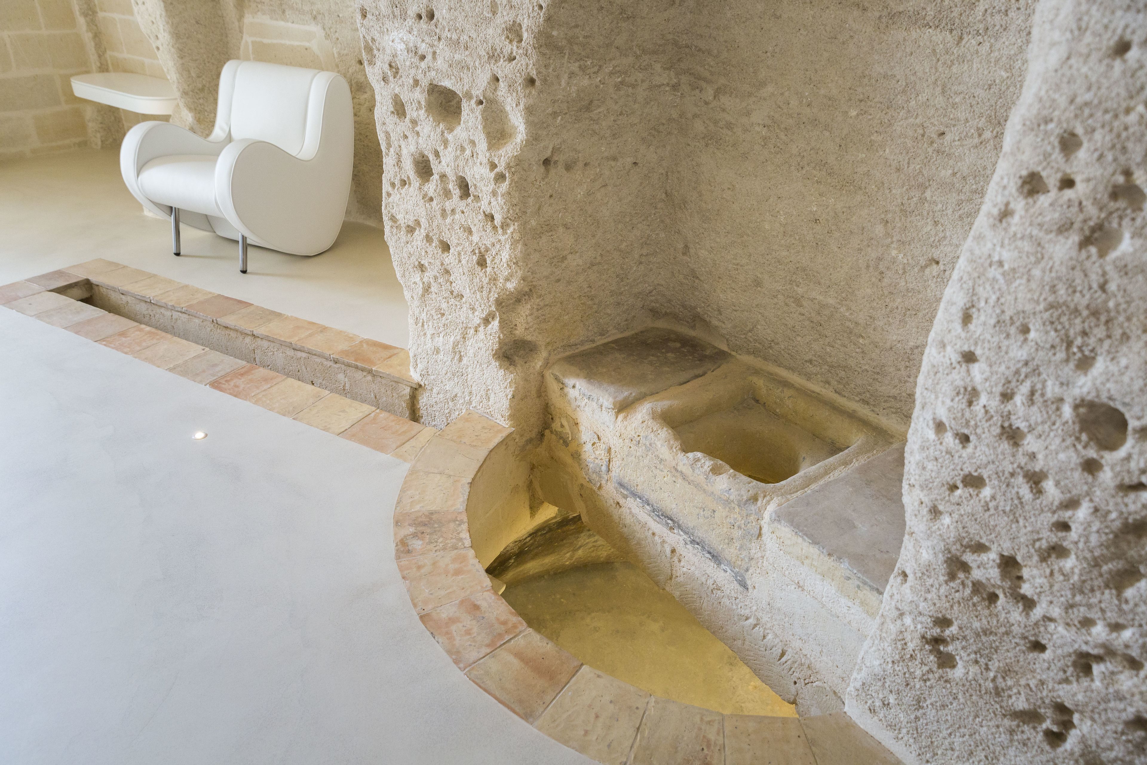 Un banco de piedra con asiento integrado y un escalón que baja a un nivel inferior.