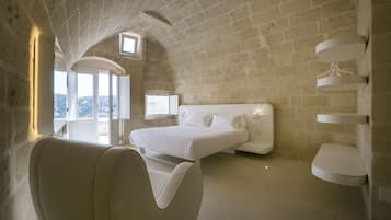 Una camera da letto moderna con un letto grande, una poltrona sagomata e un soffitto originale in mattoni.