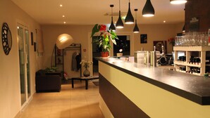 Una cocina moderna con barra, con luces colgantes, una planta en maceta y un botellero.