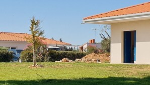 Un barrio residencial con una casa de techo de tejas rojas, puerta azul y césped bien cuidado.