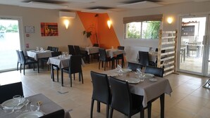Un restaurante con mesas dispuestas para comer, sillas y vistas al exterior.