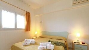 Una habitación de hotel con una cama, dos lámparas de noche, una mesita de noche y un ventanal con cortinas.
