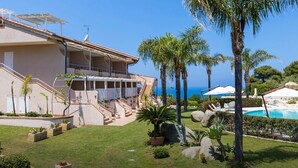 Un resort con piscina, palmeras y vista al mar.