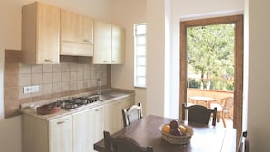 Una cocina con armarios de madera, una estufa a gas y una mesa de comedor con sillas.