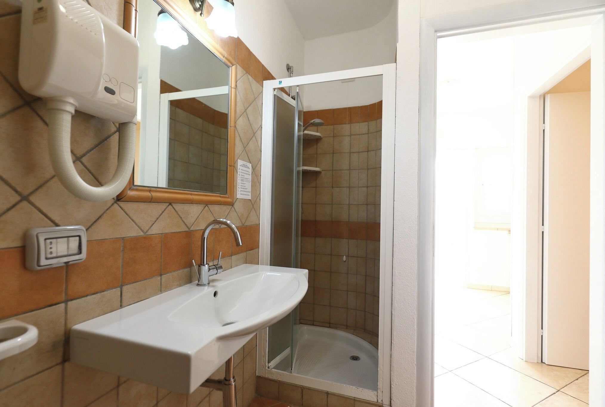 Une salle de bain avec un lavabo blanc, un miroir et une douche.
