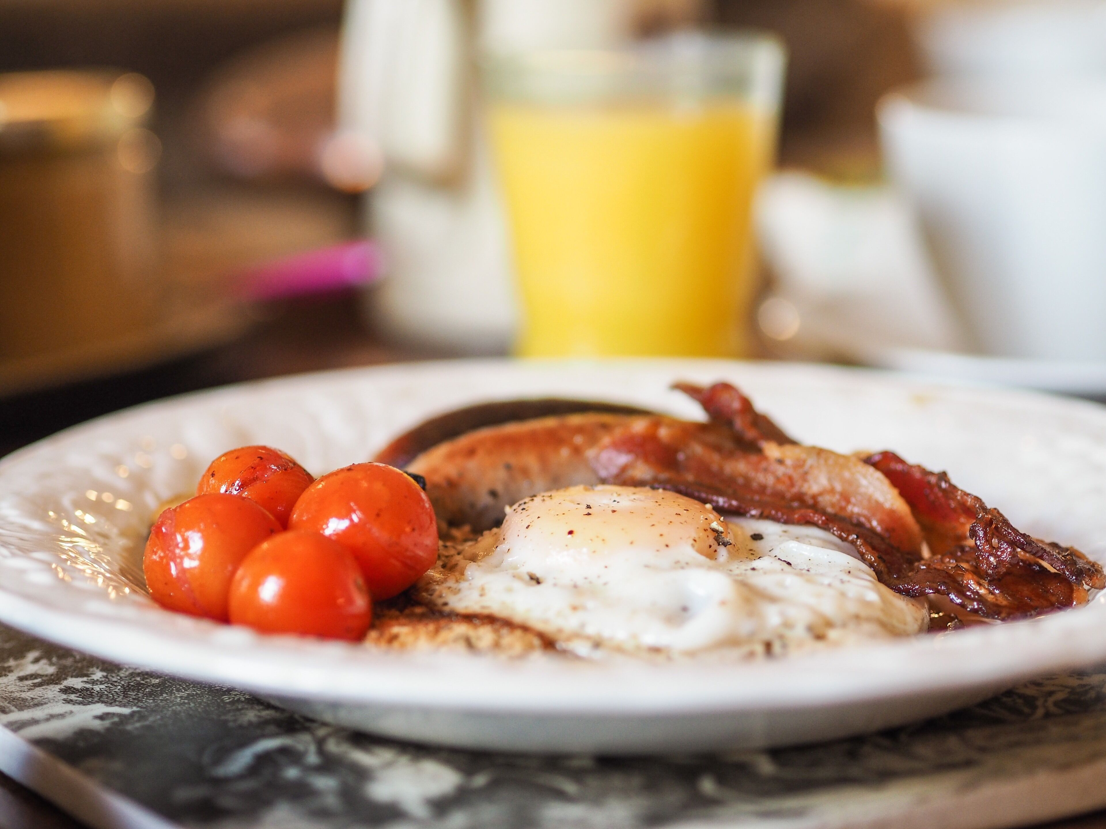 A breakfast plate with eggs, bacon, and cherry tomatoes.