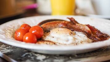 A breakfast plate with eggs, bacon, and cherry tomatoes.