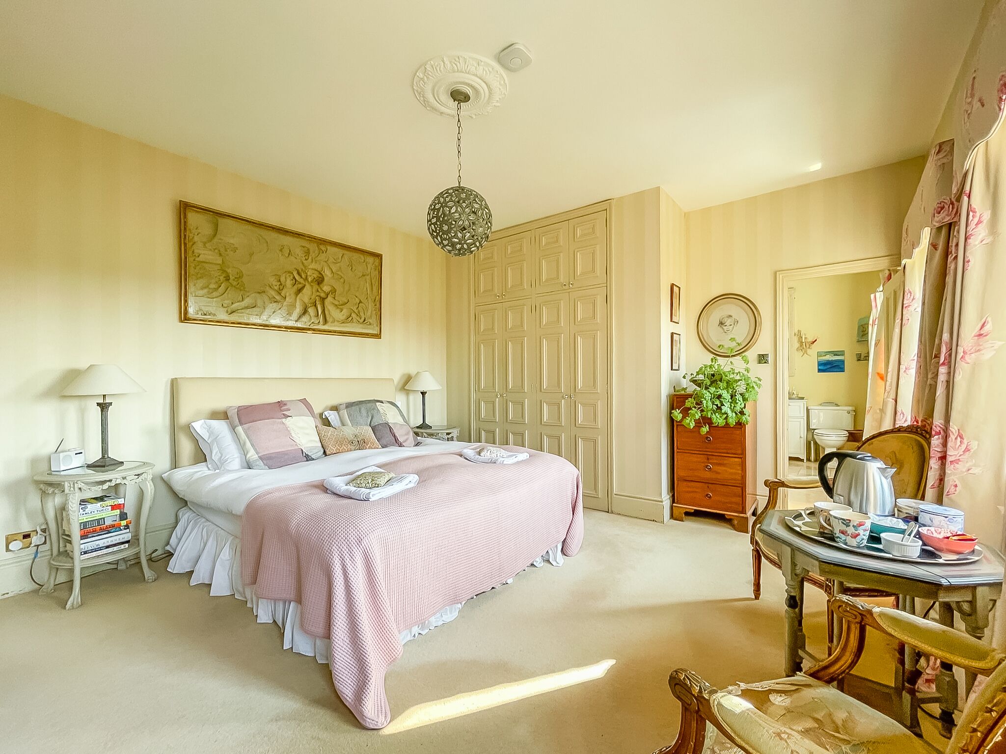 A bedroom with a large bed, a dresser, a vanity, and a chair.