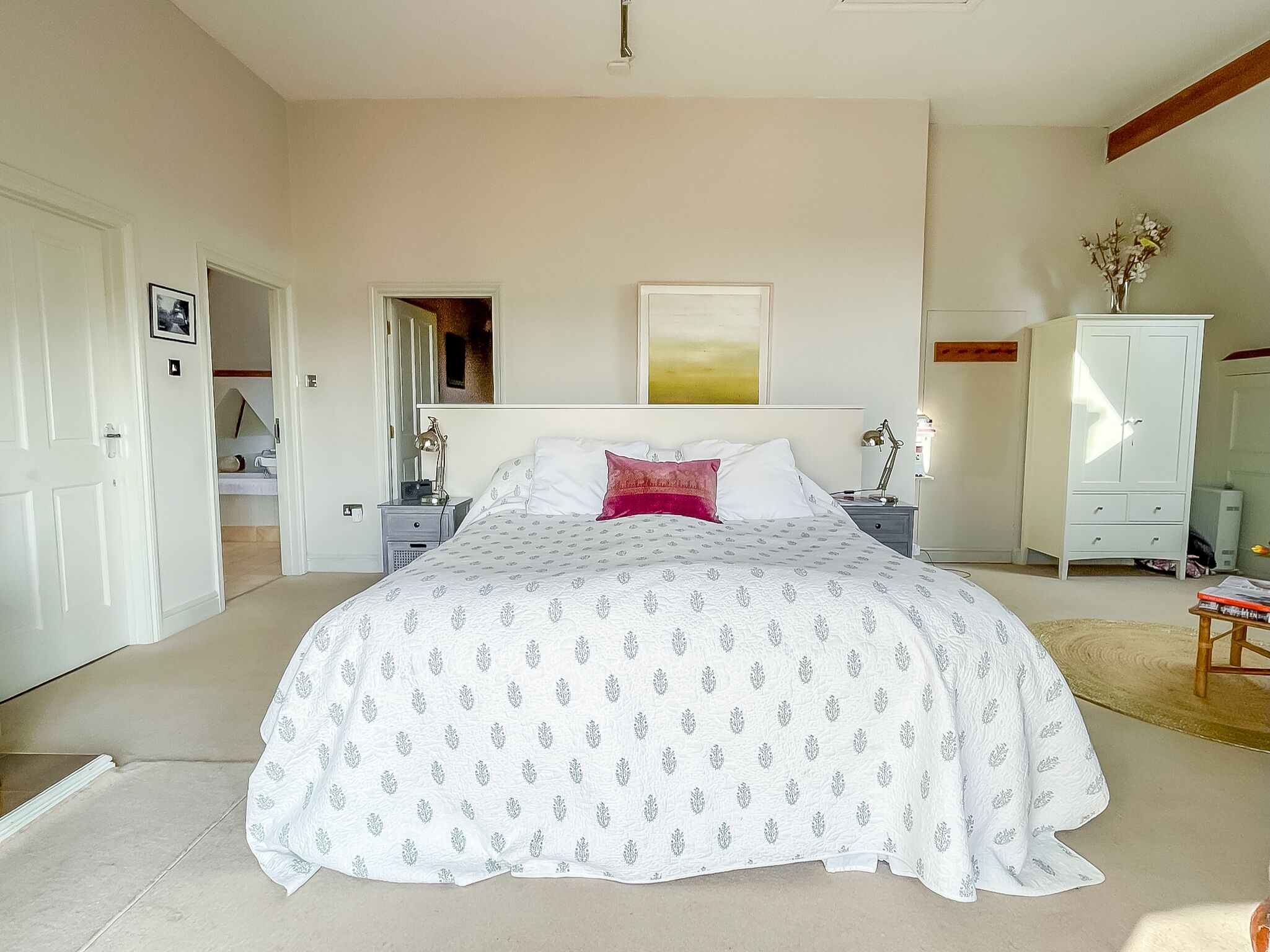 A bedroom with a large bed, a nightstand, a dresser, and a mirror.