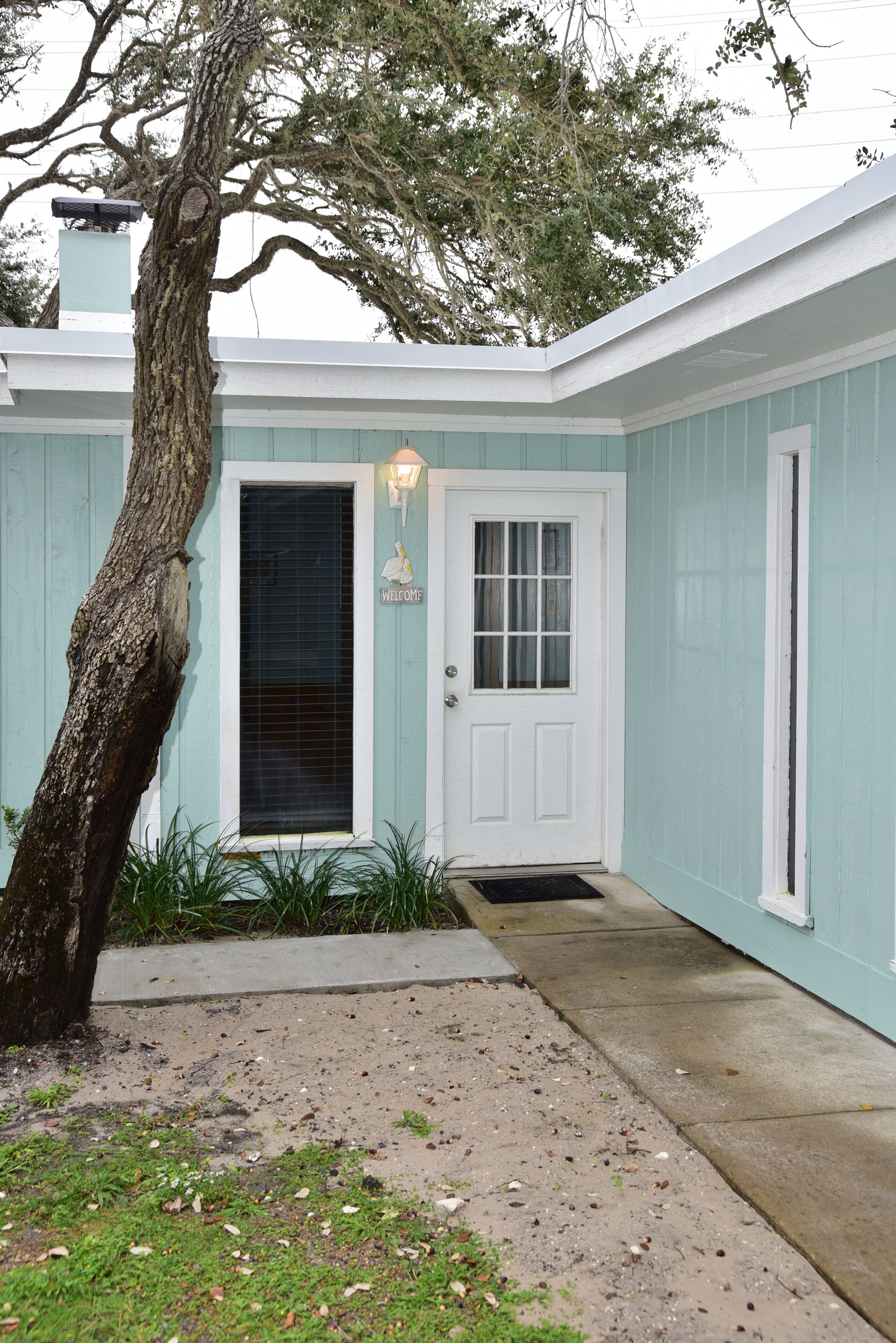 A house with a white door, a window, and a welcome sign.