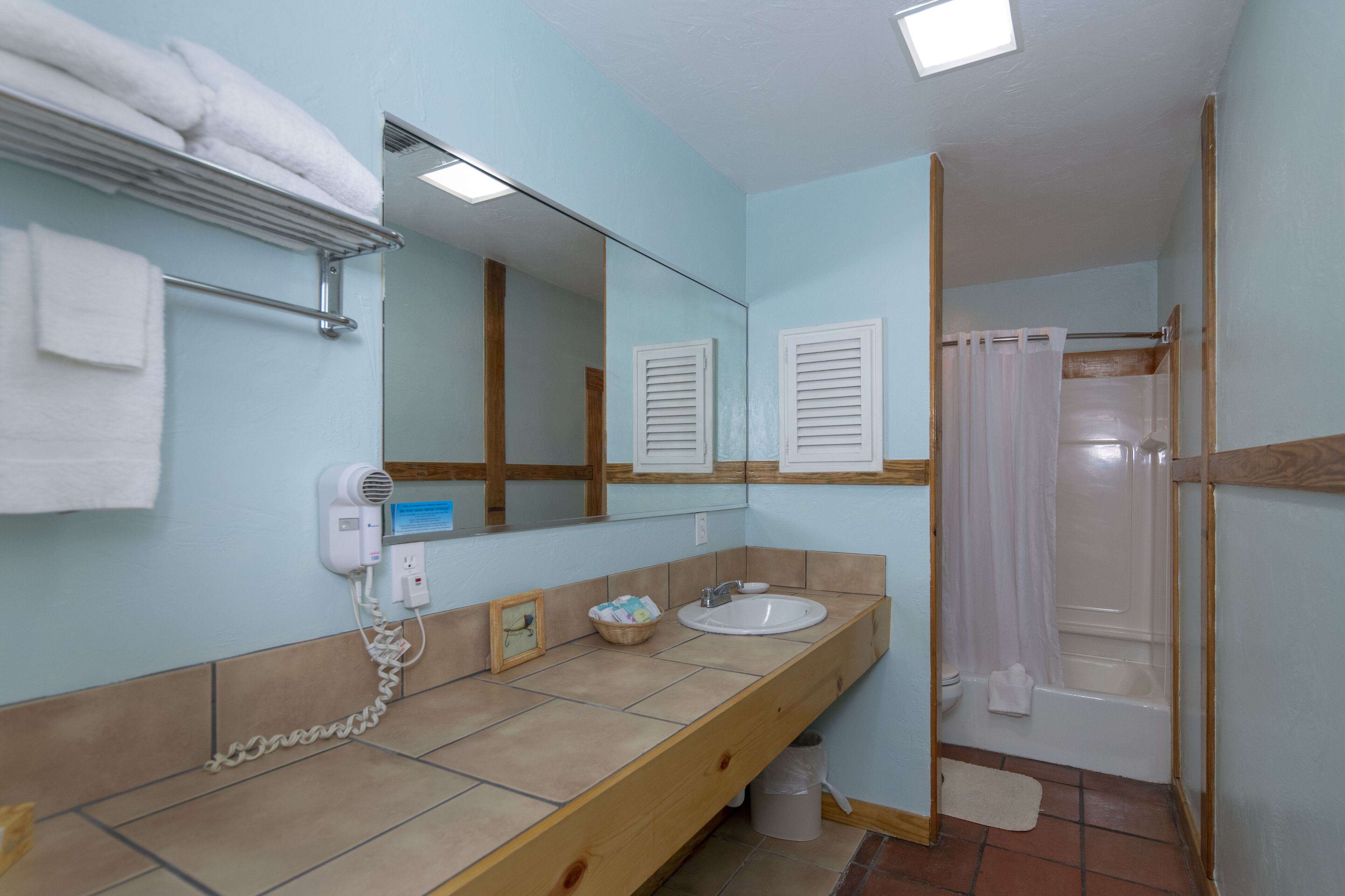Un baño con lavamanos, espejo, toallero y cabina de ducha.