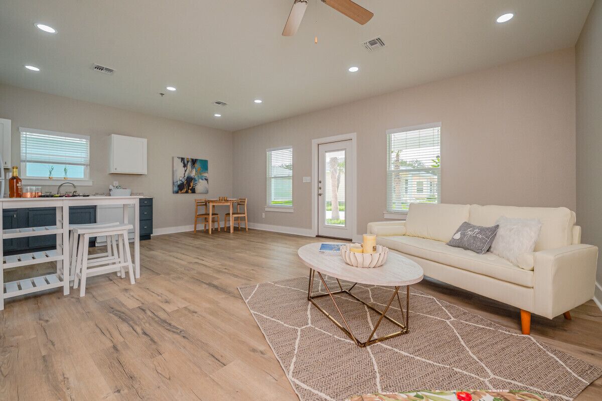 A spacious living area with a white sofa, a coffee table, and a kitchen area with a dining table.