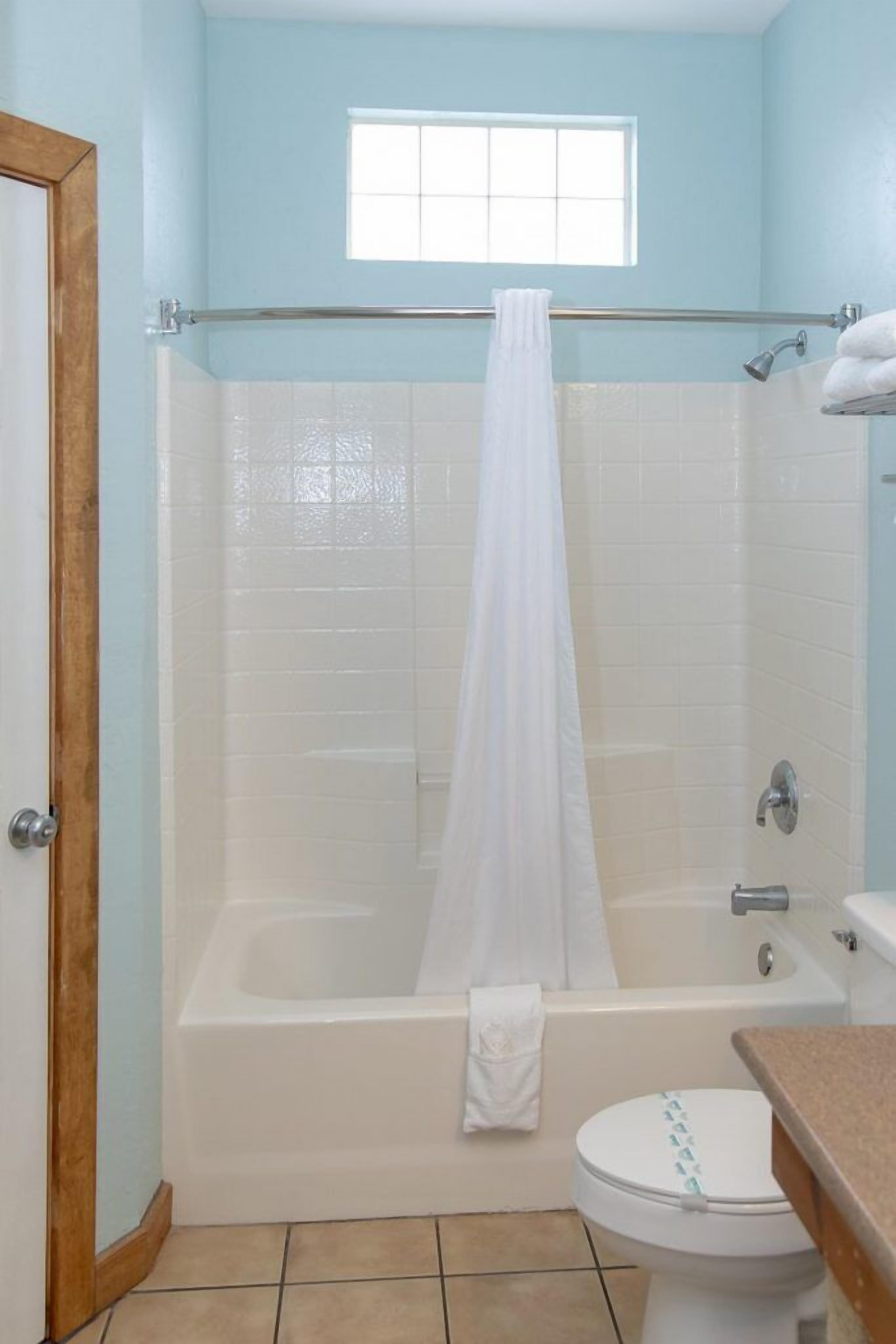 Ein Badezimmer mit Badewanne, Toilette und einem Fenster über der Dusche.