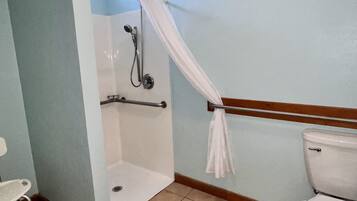 Un baño con ducha, inodoro y una silla pequeña.