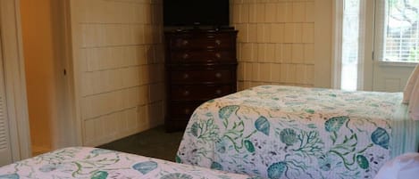 Una habitación con dos camas, un aparador y una televisión.