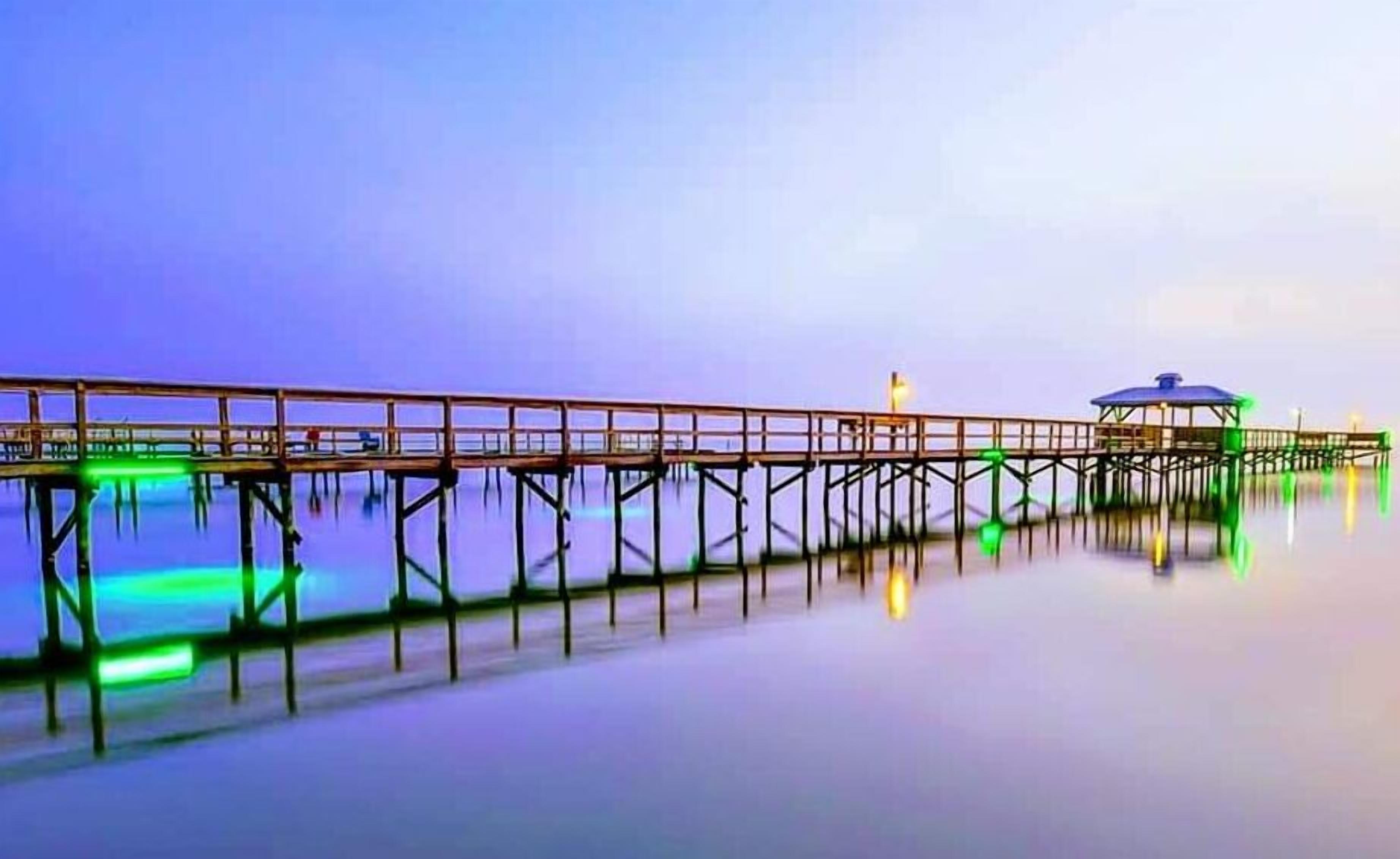 Un muelle que se adentra en aguas tranquilas con una pequeña construcción al final.