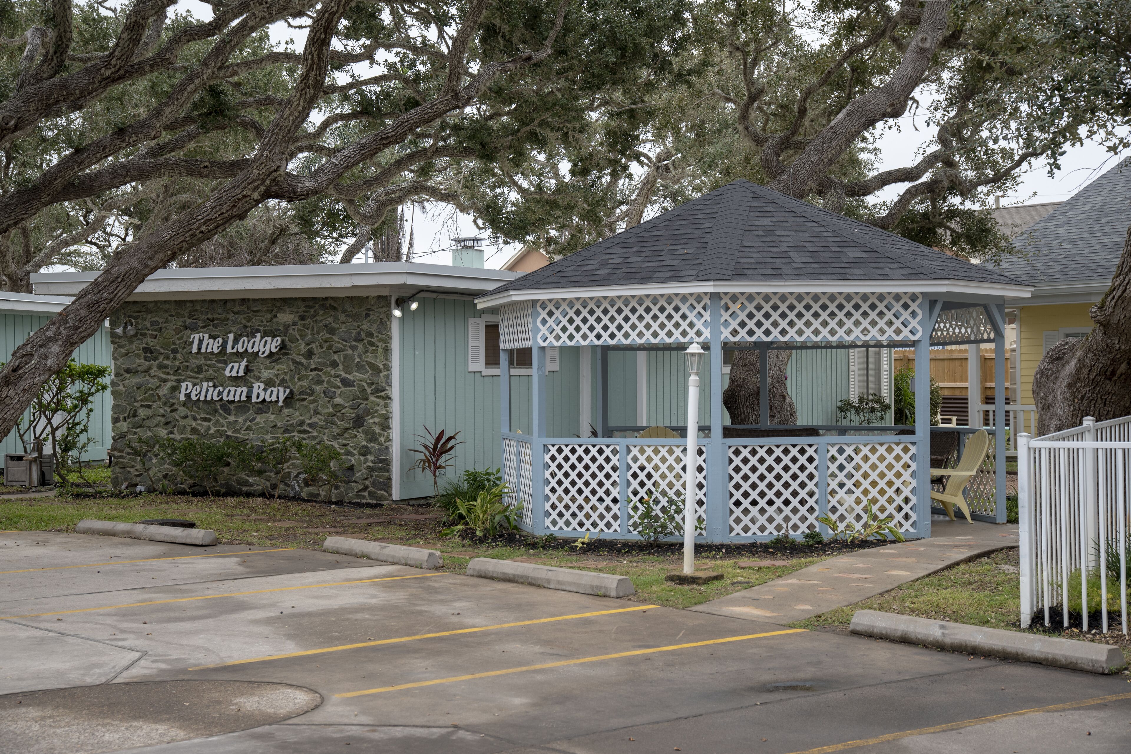 A gazebo-style structure with a stone wall and a sign reading "The Lodge at Pelican Bay."