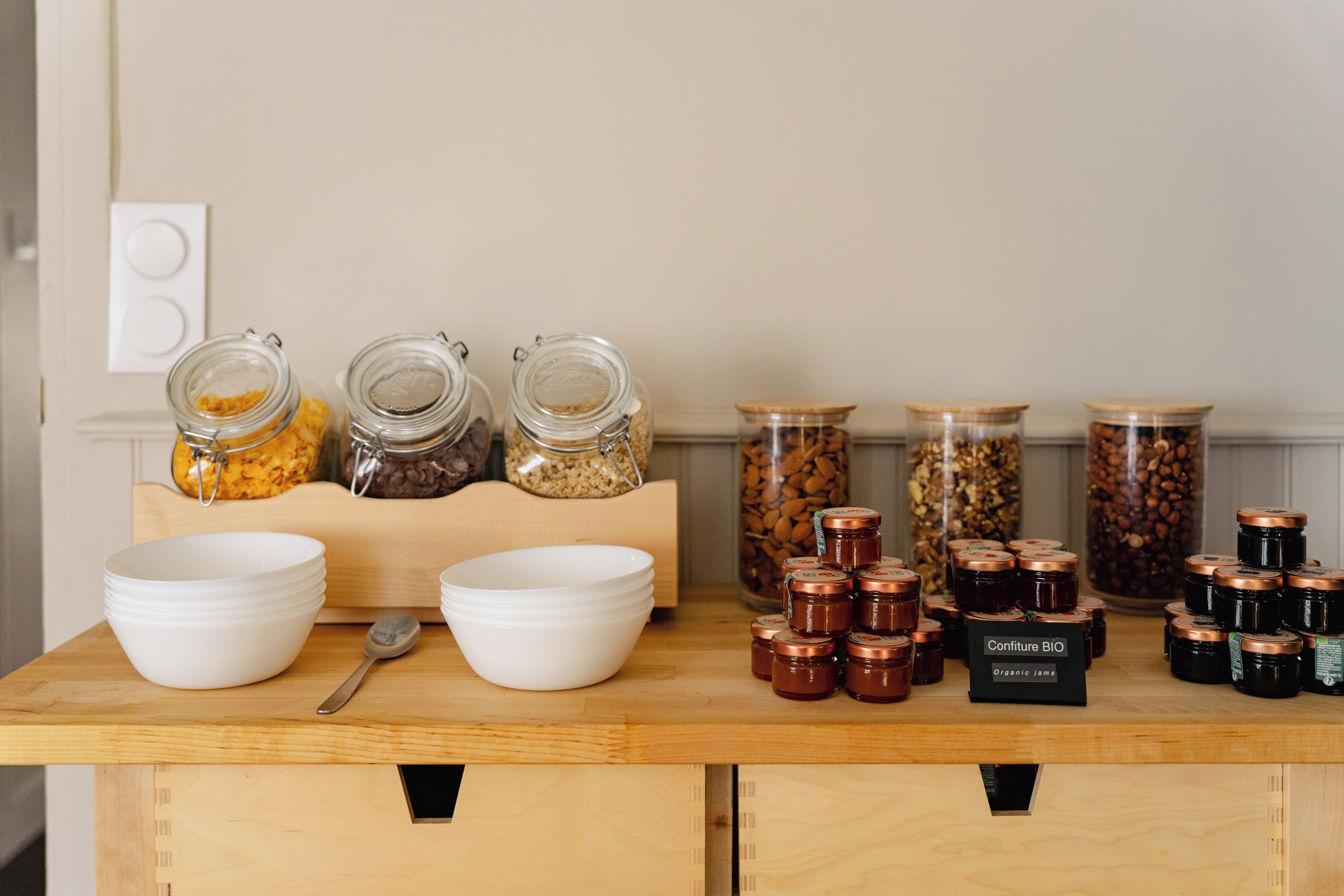 A kitchen counter with jars of food, bowls, and a sign for organic jams.