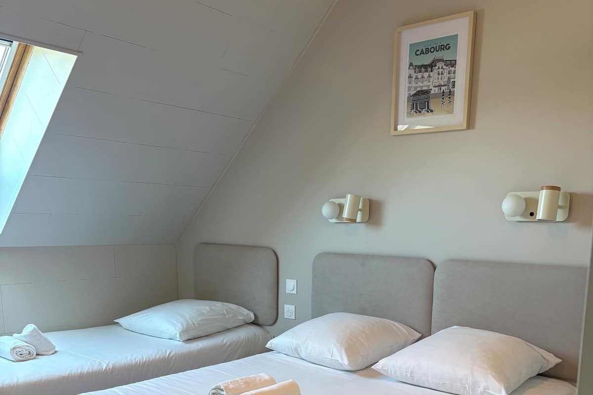 A room with two beds, a framed picture on the wall, and a skylight.