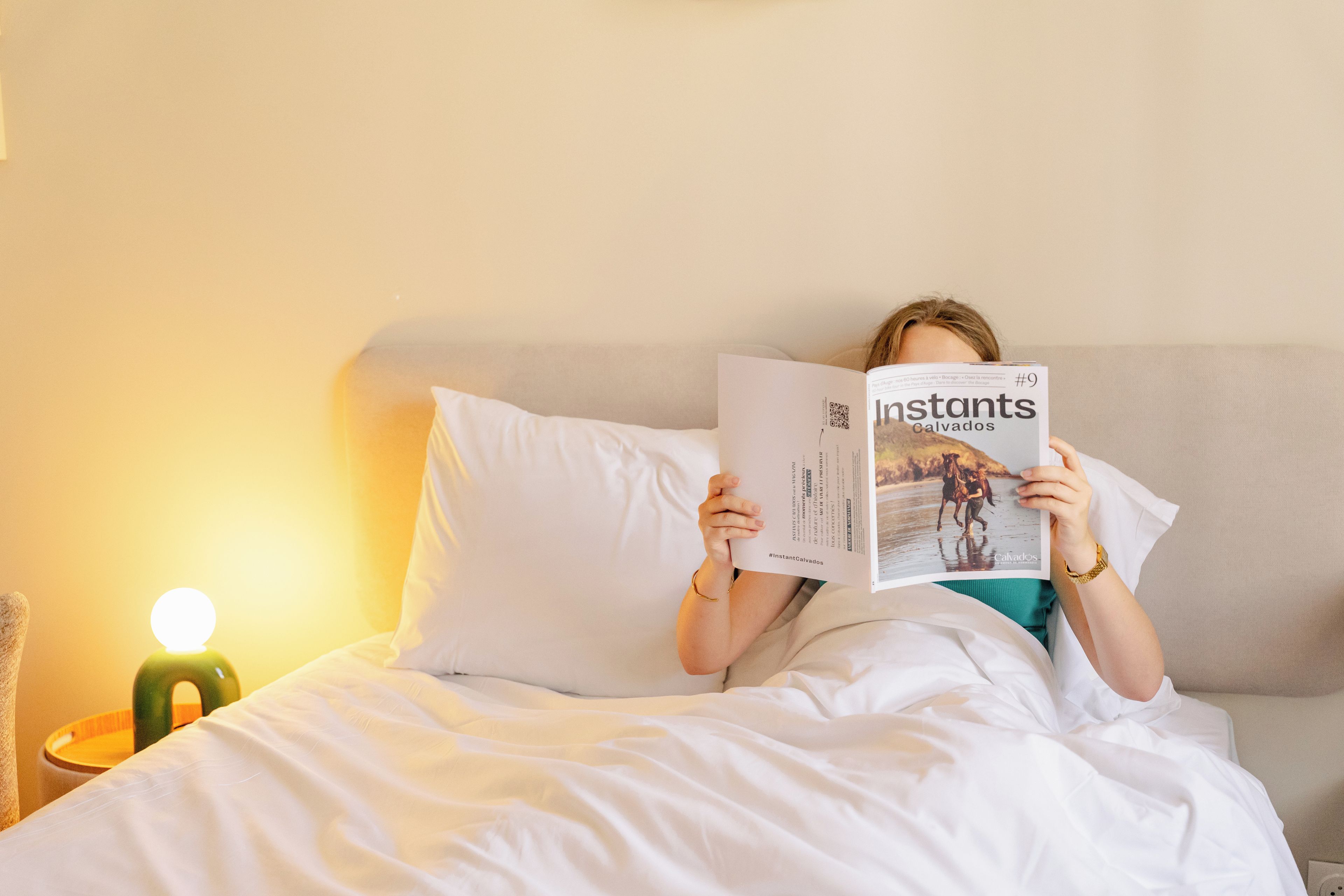 A person lying in bed reading a magazine.