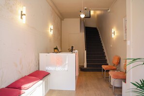 Een hotel receptie met een receptiebalie, een trap en zitplaatsen.