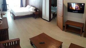 A hotel room with a bed, a TV, a wooden coffee table, and a desk with a chair. - Chiang Khan Hill Resort (Chiang Khan)