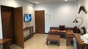 A living room with a sofa, coffee table, and a TV mounted on the wall. - Chiang Khan Hill Resort (Chiang Khan)