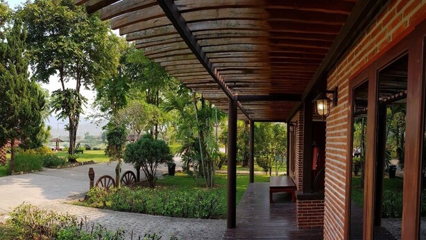 A covered outdoor area with a brick building, wooden benches, and a pathway leading to the building. - Chiang Khan Hill Resort (Chiang Khan)