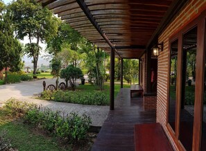 A covered outdoor area with a brick building, wooden benches, and a pathway leading to the building. - Chiang Khan Hill Resort (Chiang Khan)