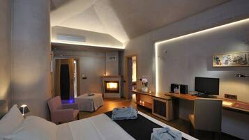 Una habitación de hotel con cama, escritorio, computadora, chimenea y zona de estar.