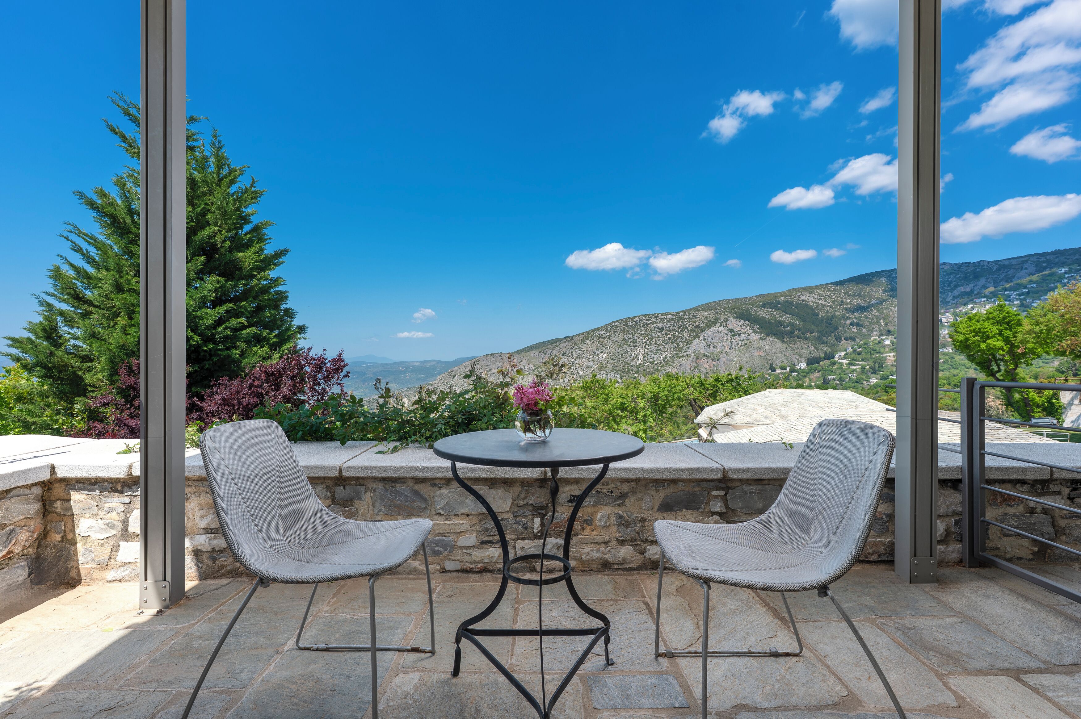 Una terrazza con tavolo e due sedie, affacciata su un paesaggio montuoso.